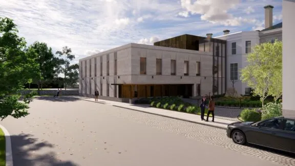 Rendering of the future Rideau Hall Adaptation Project building. The image shows a new two-storey addition with a light stone exterior, connected to the existing Rideau Hall complex and surrounded by landscaped greenery.