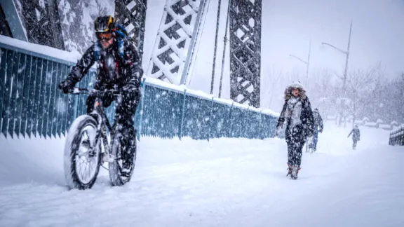 Cyclists and pedestrians on the Alexandra Bridge walkway on a snowy day. Credit: NCC