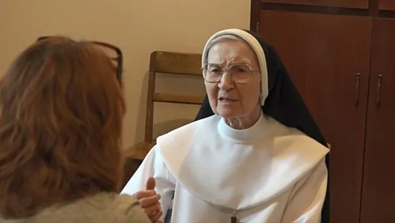 Sœur Marie-Jeanne-du-Lys, wearing a religious habit, giving an interview to Marie Roy, who is seen from behind.
