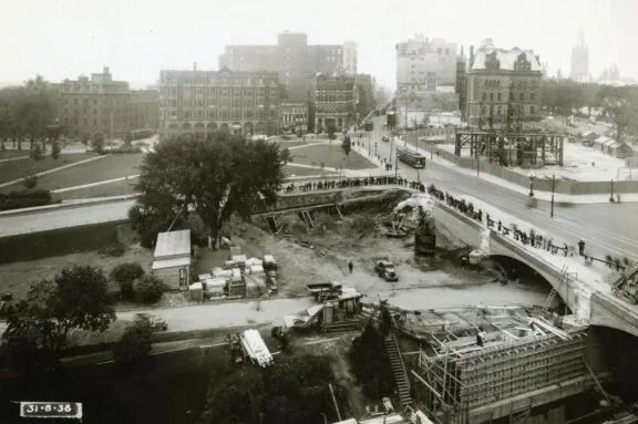 View of Connaught Place construction site and widening of the Plaza Bridge arch, with Elgin and Wellington streets in the background. August 31, 1938. Credit: Library and Archives Canada / E999909167-u