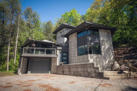 House made of concrete blocks, showing windows and a balcony over the garage door.