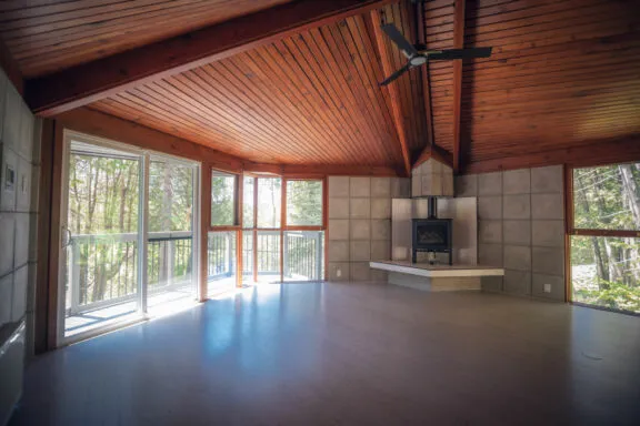 Room with a balcony access, a fireplace and a wood-slat ceiling.