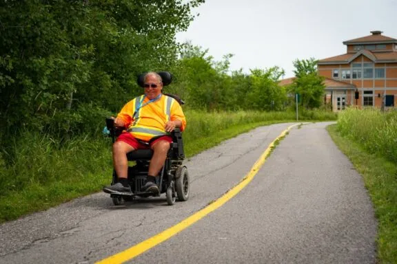 Person using a four-wheeled electric scooter on the Capital Pathway in Gatineau Park, near the Relais plein air.