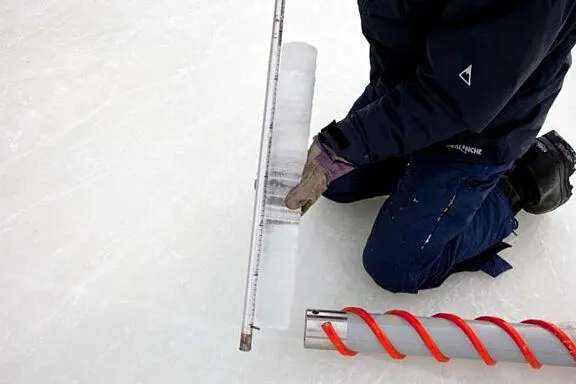 Membre de l'équipe qui tient une carotte de glace sur la patinoire du canal Rideau.