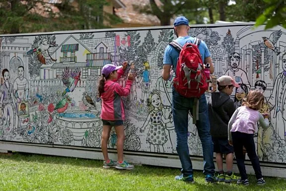 Une famille qui dessine sur le murale géante à colorier
