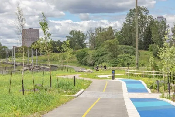 Voie cyclable et sentier piétonnier séparés, avec signalisation de la vitesse (maximum 10 km/h), avec une personne en arrière-plan.