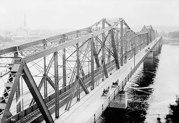 A historical image of Alexandra Bridge that features horse-drawn carriages crossing along the East side of the bridge, circa 1900. Credit: LAC/Topley/PA-009430