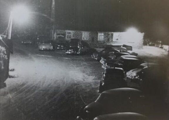 A black and white picture of cars parked outside the new Gray barn on dance night. Every Saturday night in the 1940s and 1950s, the hayloft hosted the famous Gray family barn dances.