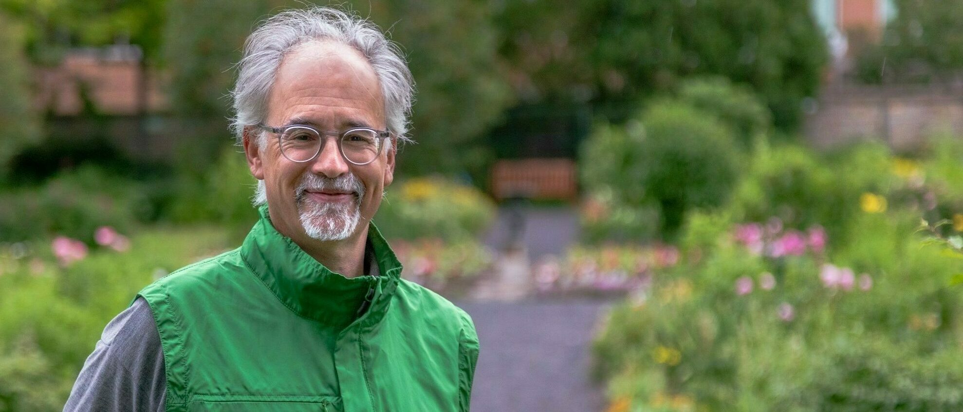 Bénévole portant une veste de bénévole de la CCN, dans un jardin, face à l’appareil photo