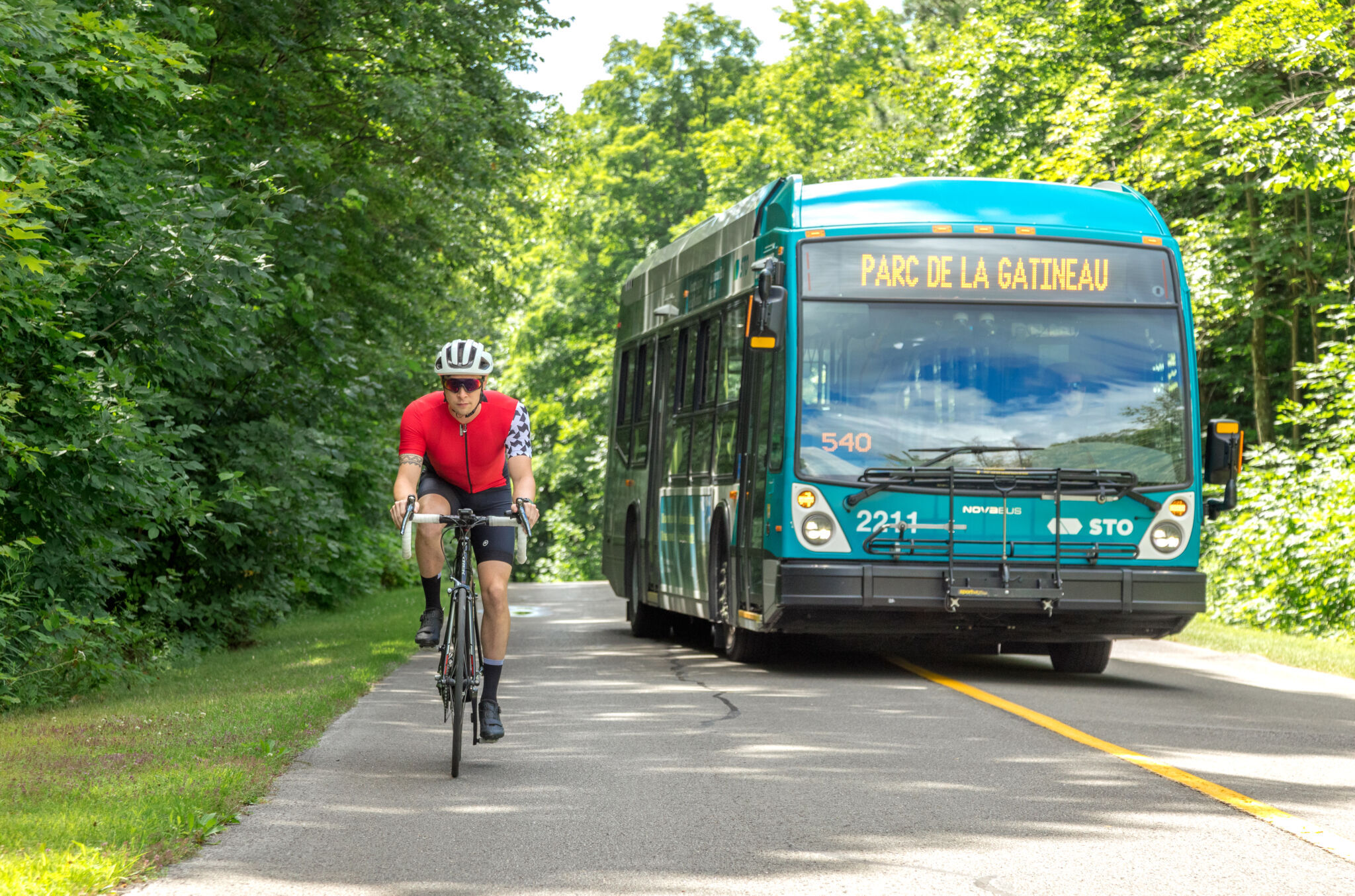 Navette du parc de la Gatineau dépassant un cycliste sur une promenade étroite.