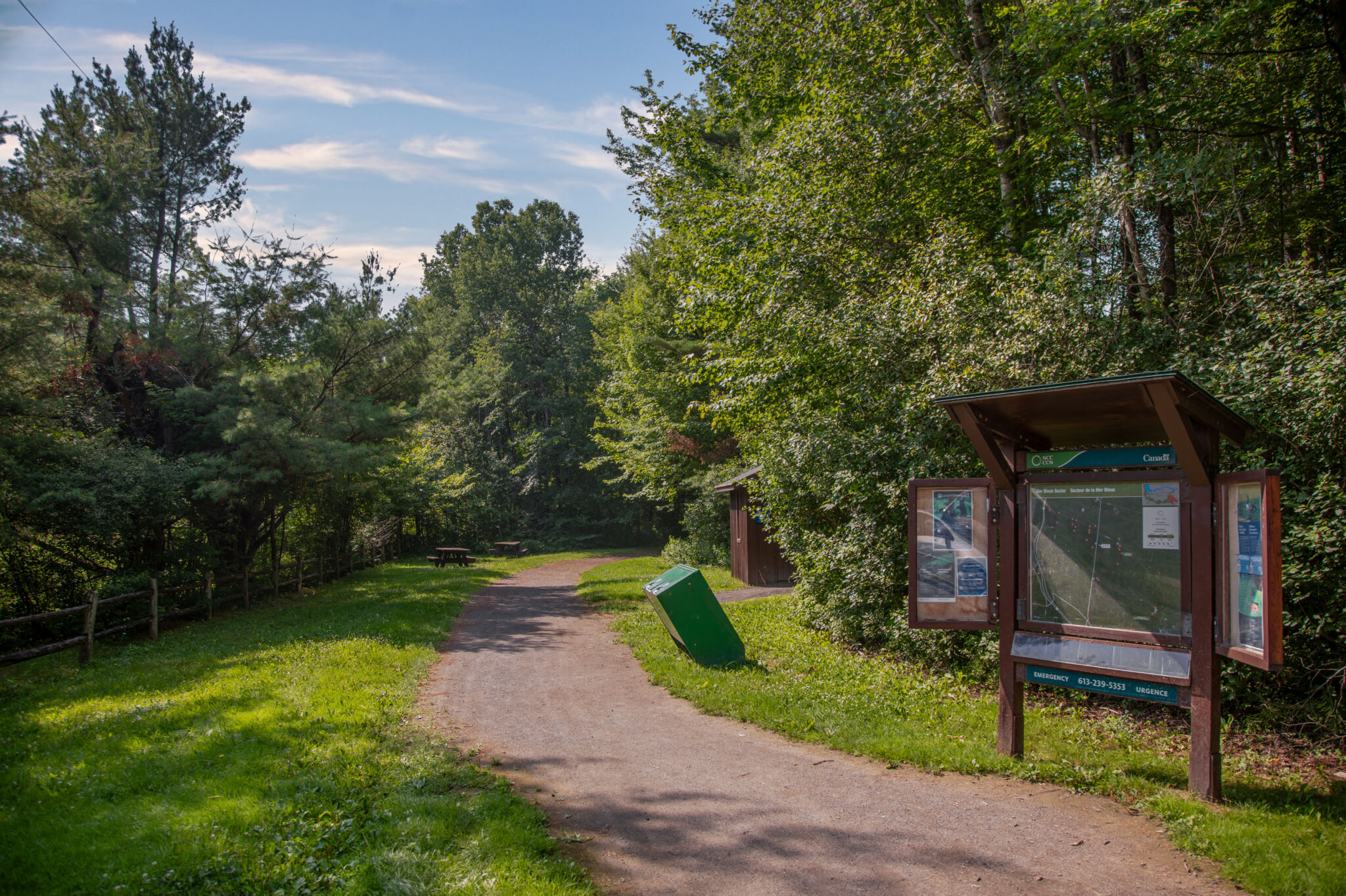 Un sentier de la Ceinture de verdure avec des panneaux indicateurs et des arbres environnants