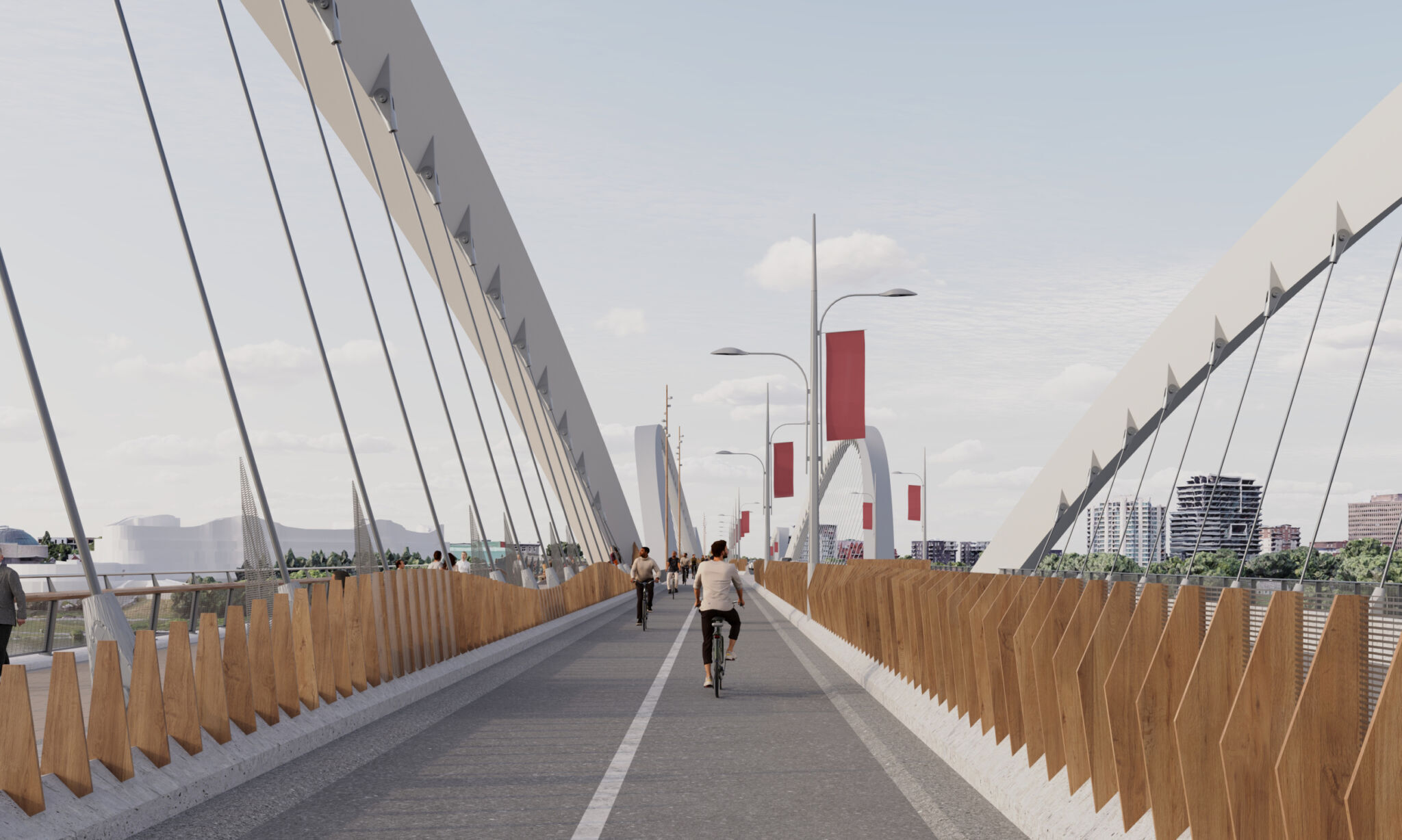 Vue de la piste cyclable du pont du point de vue d’un cycliste. Le pont est doté de grandes structures de support incurvées et d’écrans en bois le long des barrières protectrices de chaque côté. Plusieurs cyclistes et piétons sont sur le sentier. L’arrière-plan comprend des bâtiments, de la verdure, des lampadaires et des bannières rouges suspendues à des poteaux le long du pont.