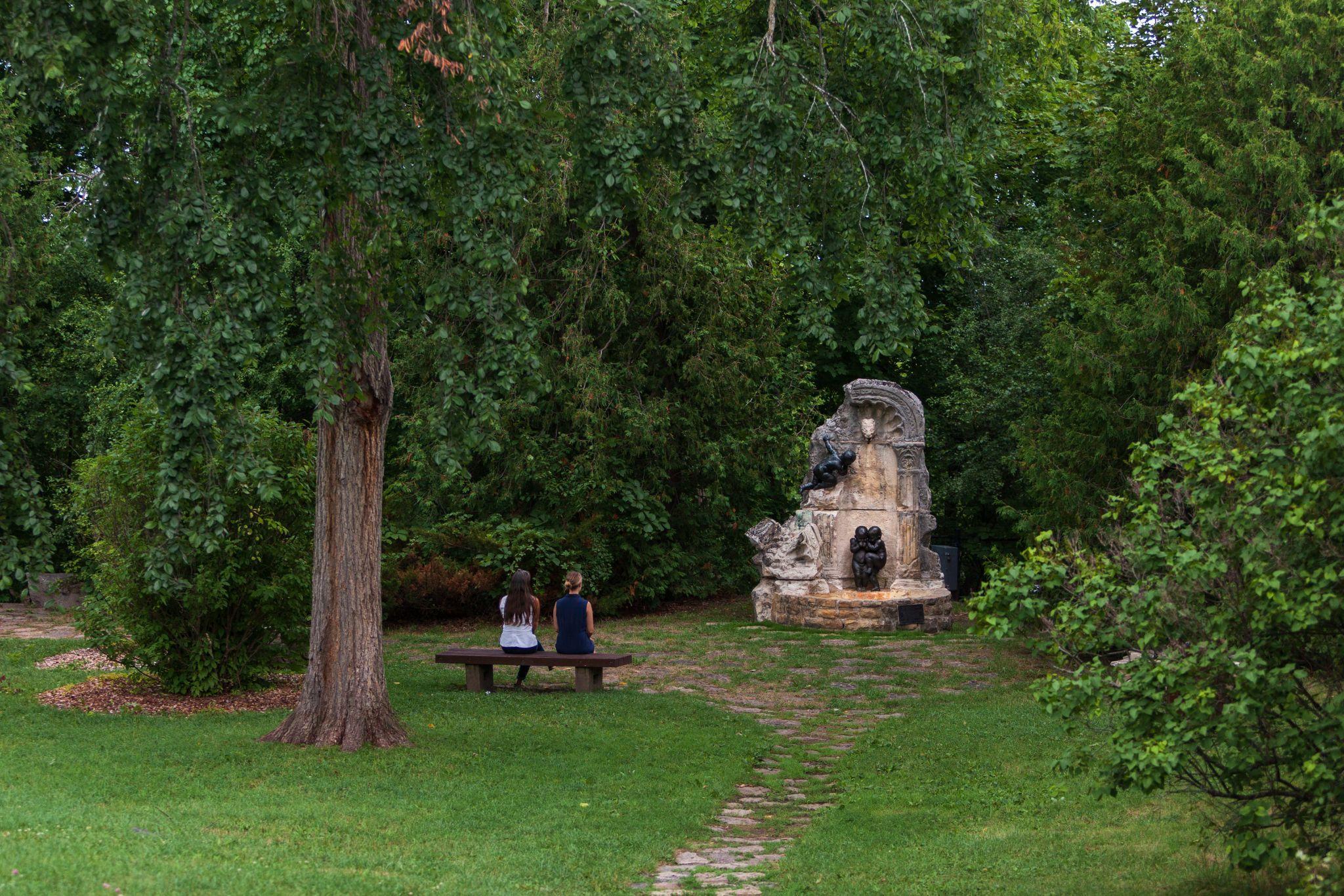 Des personnes assises sur un banc, qui regardent des ruines au parc de Rockcliffe à Ottawa.