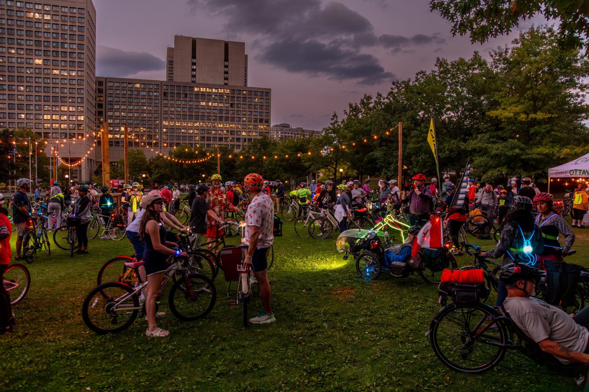 De nombreux vélos à l’extérieur en soirée sous des lumières.