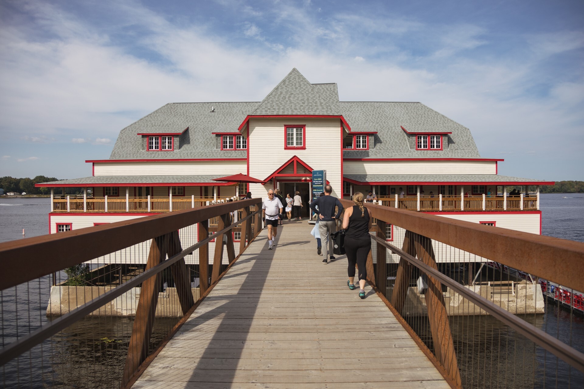 La passerelle menant à la maison riveraine de la CCN. Le ciel est bleu avec des nuages.